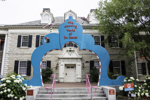 Two-story tall curved blue and red and white striped arch is doorway to the Dr. Seuss museum.